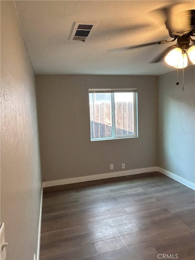 empty room with ceiling fan, dark hardwood / wood-style flooring, and a textured ceiling