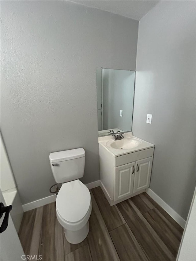 bathroom with toilet, vanity, and wood-type flooring