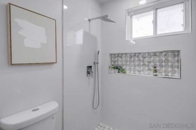 bathroom with toilet and a tile shower