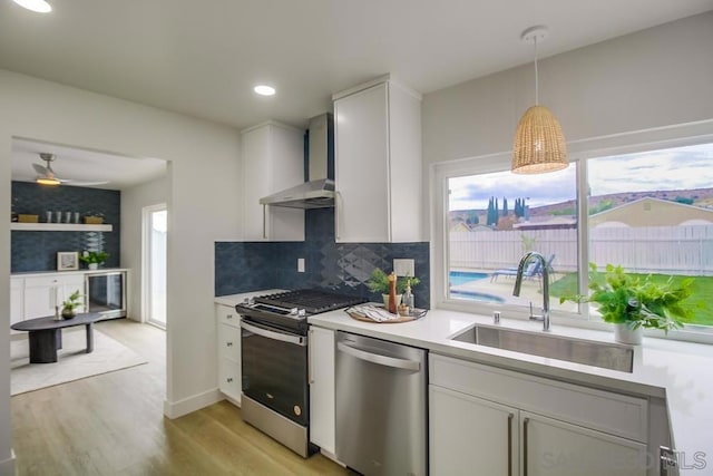 kitchen with sink, white cabinetry, appliances with stainless steel finishes, and wall chimney exhaust hood