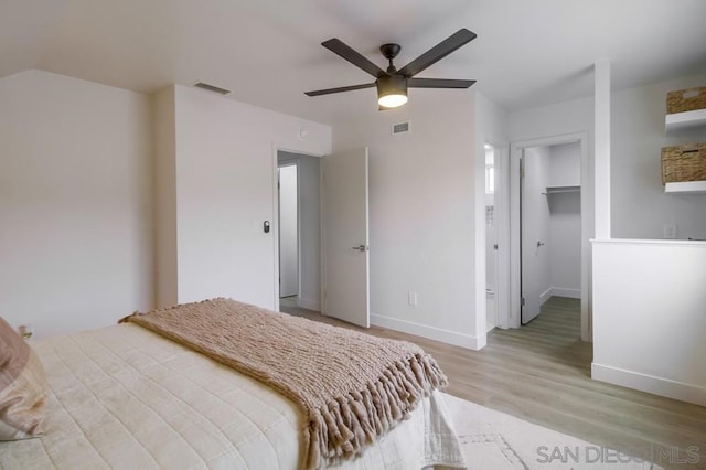 bedroom featuring ceiling fan, a closet, a spacious closet, and light hardwood / wood-style flooring