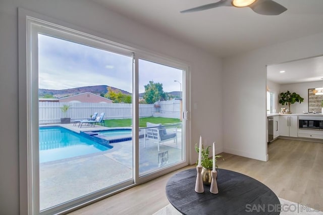 doorway featuring ceiling fan, a wealth of natural light, a mountain view, and light hardwood / wood-style flooring