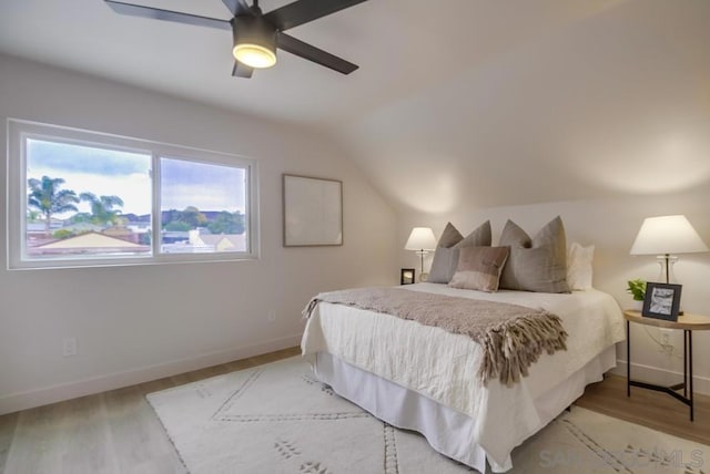 bedroom with ceiling fan, light hardwood / wood-style flooring, and lofted ceiling