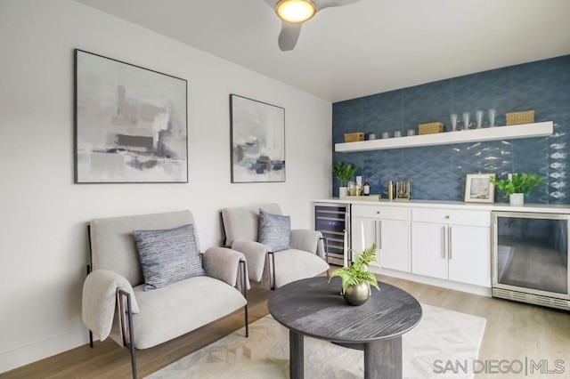 sitting room with ceiling fan, light hardwood / wood-style flooring, and wine cooler