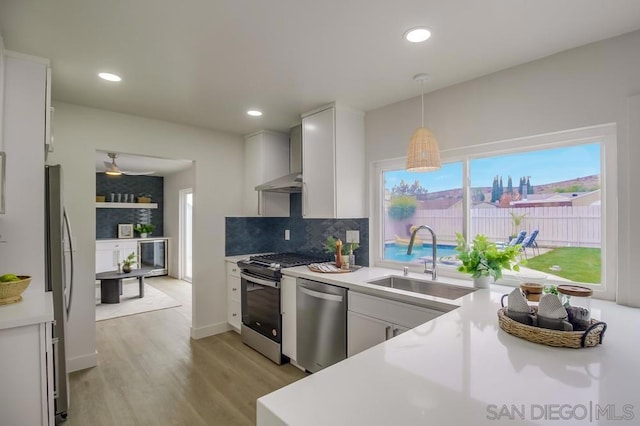 kitchen with stainless steel appliances, white cabinets, hanging light fixtures, and sink