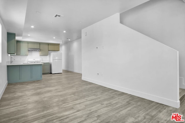 interior space with white fridge, sink, green cabinetry, light hardwood / wood-style flooring, and stove