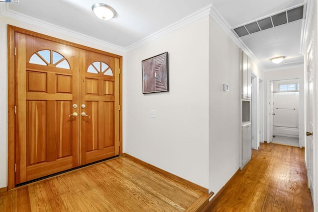 entryway with light wood-type flooring and ornamental molding