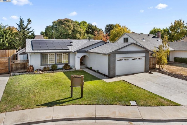 single story home featuring a garage, a front lawn, and solar panels