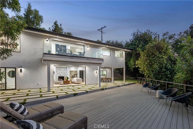 back house at dusk featuring a balcony and an outdoor living space