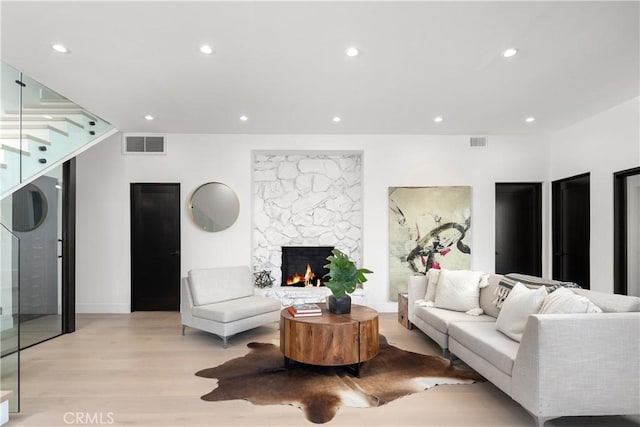 living room featuring light wood-type flooring and a stone fireplace