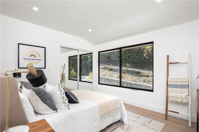 bedroom featuring light hardwood / wood-style floors, a closet, and vaulted ceiling