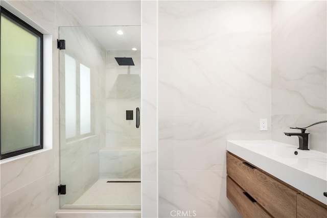 bathroom featuring a shower with shower door and vanity