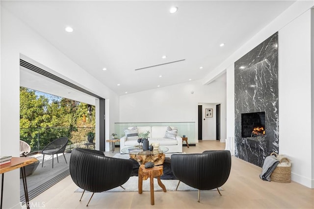 living room with light wood-type flooring, lofted ceiling, and a fireplace