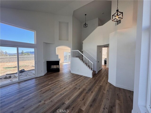 unfurnished living room featuring a multi sided fireplace, dark hardwood / wood-style floors, and a towering ceiling