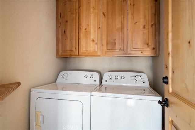 laundry area featuring washing machine and clothes dryer and cabinets