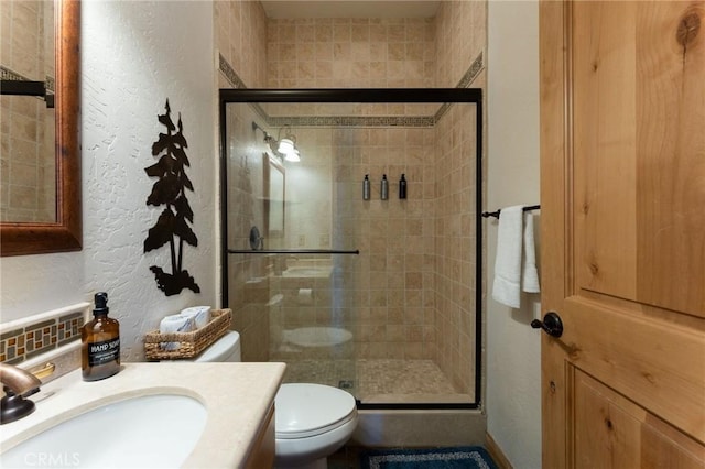 bathroom with toilet, tasteful backsplash, a shower with door, and vanity