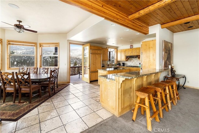 kitchen with tasteful backsplash, ceiling fan, stone counters, a breakfast bar, and kitchen peninsula