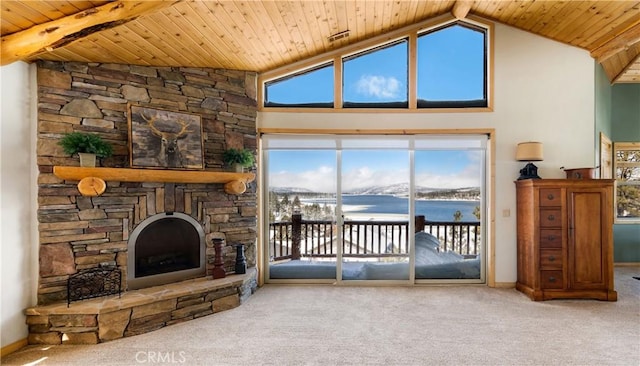 carpeted living room with wood ceiling, a water view, a stone fireplace, and high vaulted ceiling