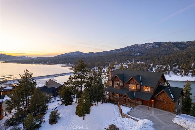 snowy aerial view with a water and mountain view