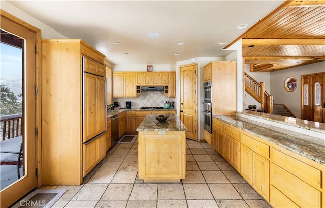 kitchen featuring a kitchen island, decorative backsplash, stainless steel dishwasher, and light stone counters