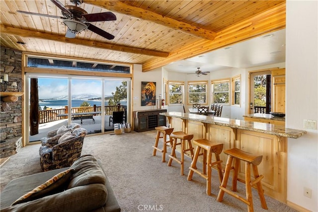 carpeted living room with ceiling fan, wooden ceiling, beam ceiling, and a water view