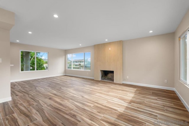 unfurnished living room with a large fireplace and light wood-type flooring