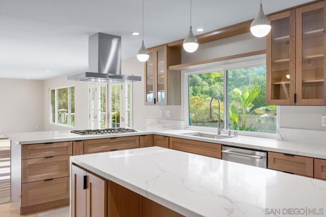 kitchen with pendant lighting, sink, light stone countertops, appliances with stainless steel finishes, and island range hood