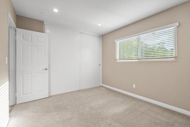 unfurnished bedroom featuring light colored carpet and a closet