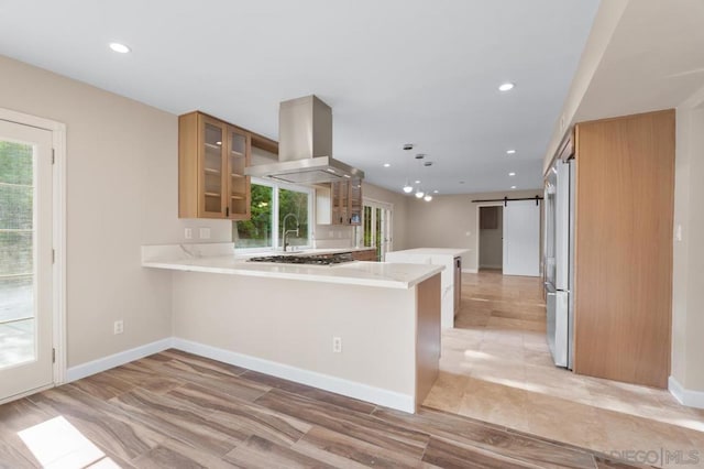 kitchen featuring kitchen peninsula, refrigerator, island range hood, and a barn door