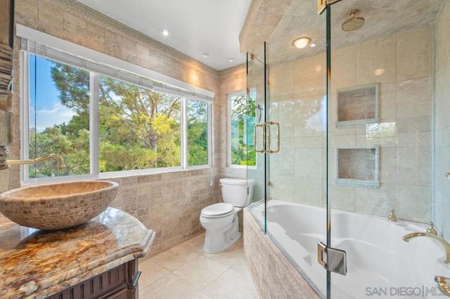 bathroom with toilet, vanity, tile walls, and a healthy amount of sunlight