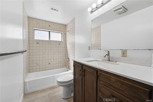 full bathroom with toilet, vanity, and tiled shower / bath combo