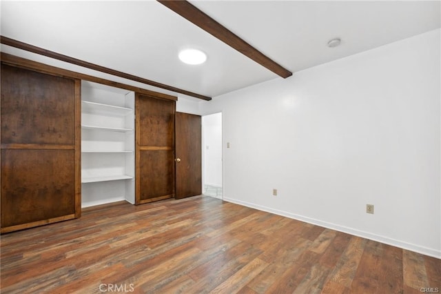 unfurnished bedroom with hardwood / wood-style flooring, a closet, and beamed ceiling