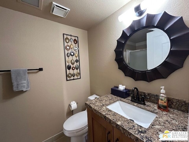 bathroom featuring a textured ceiling, toilet, and vanity