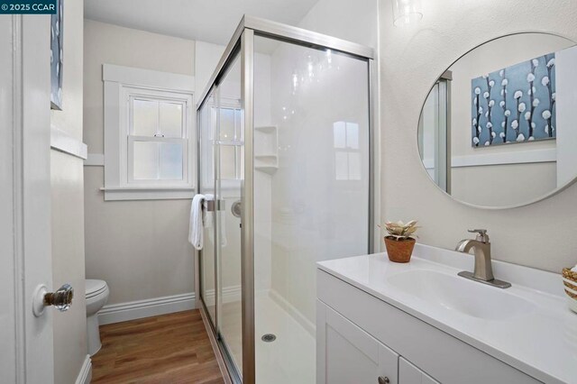 bathroom with vanity, toilet, an enclosed shower, and wood-type flooring