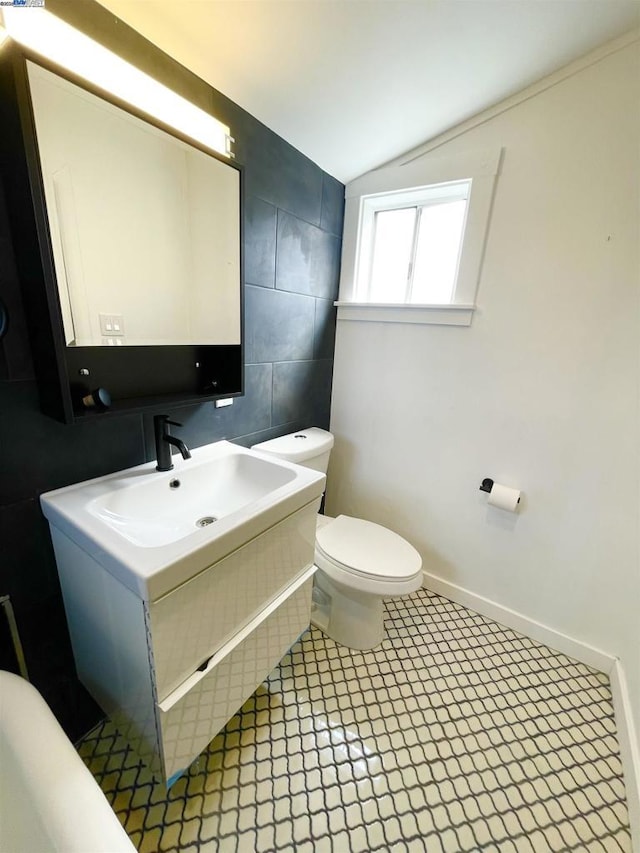 bathroom with toilet, lofted ceiling, and sink