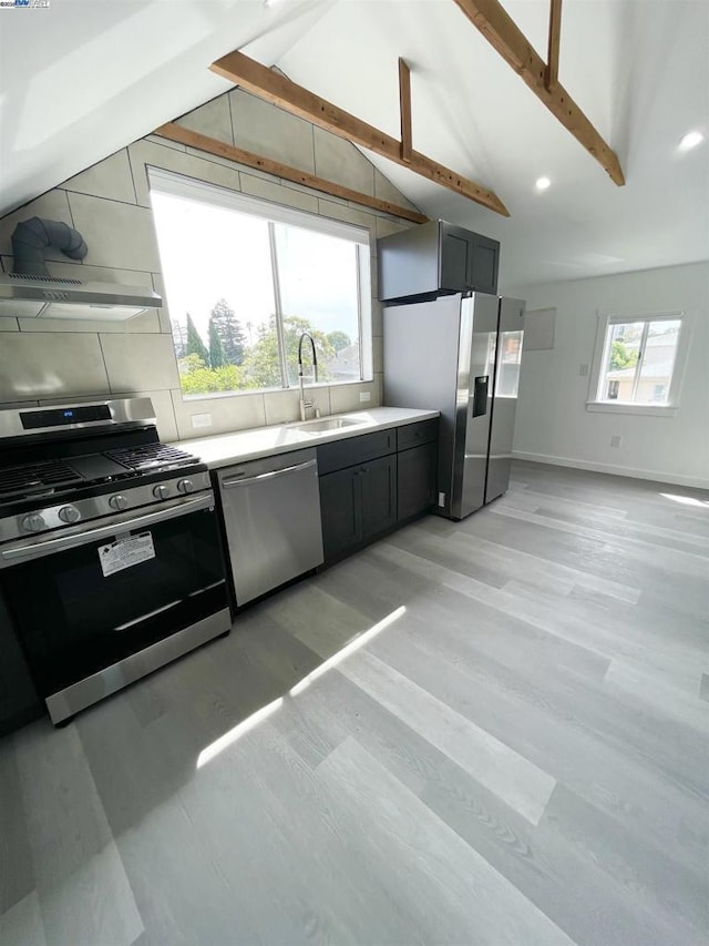 kitchen with light hardwood / wood-style floors, sink, appliances with stainless steel finishes, and lofted ceiling with beams