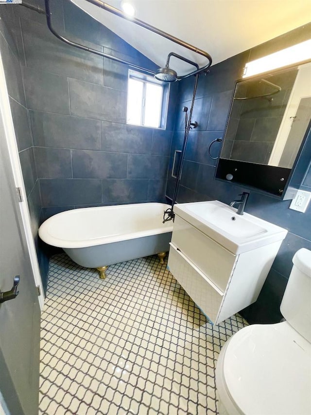 full bathroom with vaulted ceiling, toilet, tiled shower / bath, and vanity