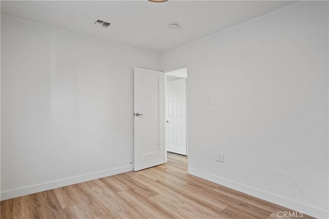 empty room with light hardwood / wood-style flooring and ornamental molding