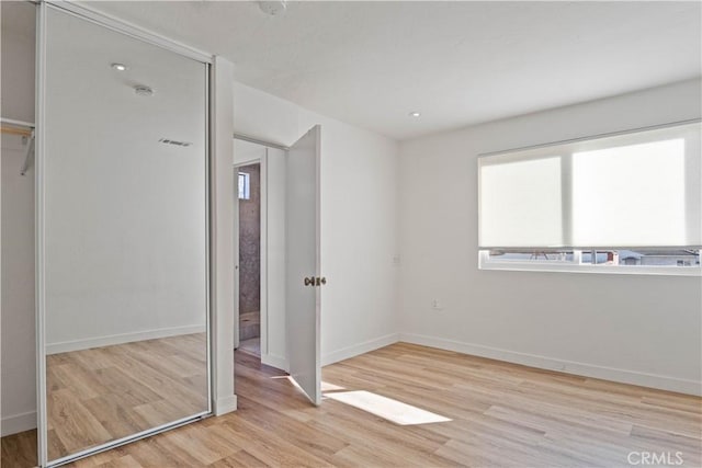 unfurnished bedroom with light hardwood / wood-style floors and a closet