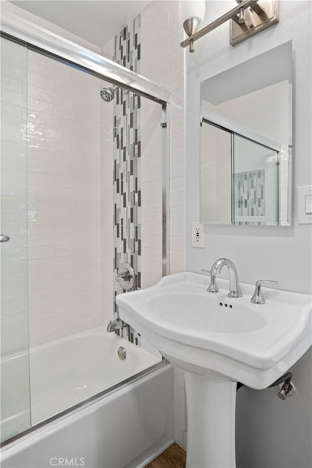 bathroom featuring bath / shower combo with glass door and sink