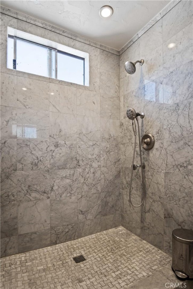 bathroom with tiled shower and a healthy amount of sunlight