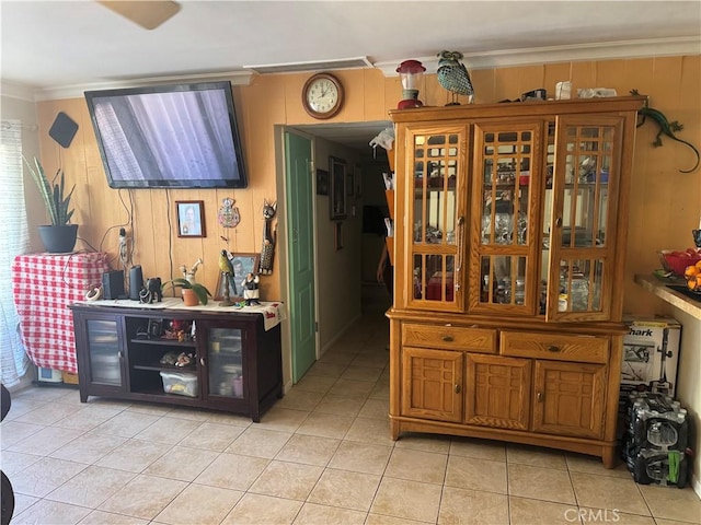 interior space with crown molding, light tile patterned floors, and wood walls