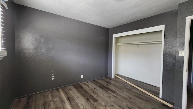 unfurnished bedroom with dark wood-type flooring and a closet