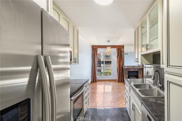 kitchen featuring backsplash, dark stone countertops, sink, stainless steel appliances, and cream cabinetry