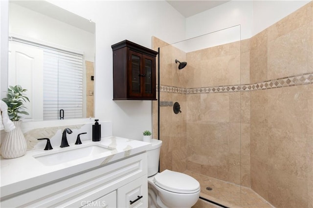 bathroom featuring toilet, vanity, and a tile shower