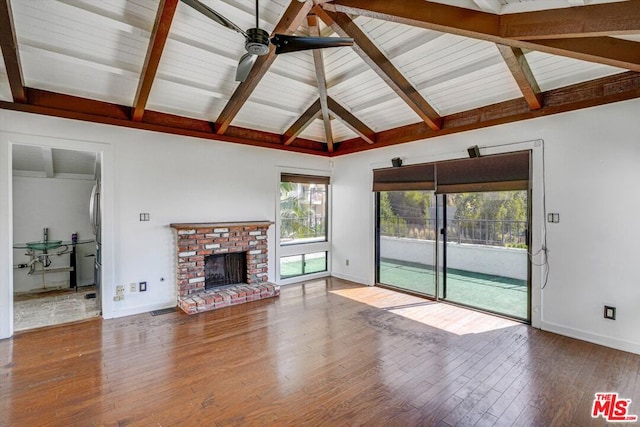 unfurnished living room with a brick fireplace, hardwood / wood-style floors, vaulted ceiling with beams, and ceiling fan