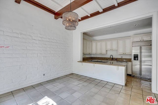 kitchen featuring cream cabinetry, kitchen peninsula, built in fridge, pendant lighting, and sink