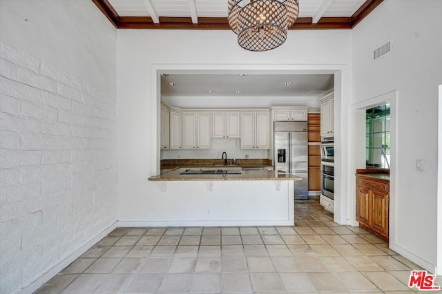 kitchen featuring kitchen peninsula, sink, beamed ceiling, an inviting chandelier, and built in refrigerator