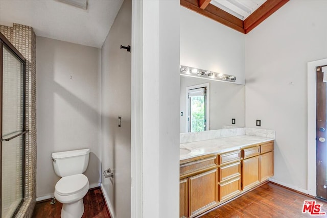 bathroom featuring hardwood / wood-style flooring, toilet, vanity, and lofted ceiling