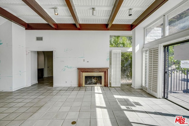 unfurnished living room featuring light tile patterned floors, a towering ceiling, and beamed ceiling